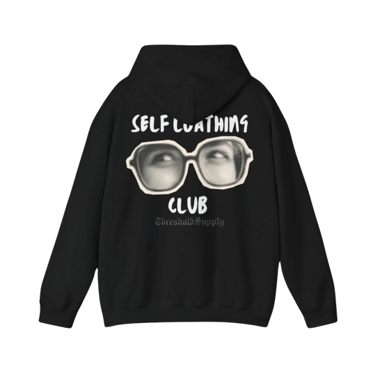 Self Loathing Club hoodie with blurred badge emblem and bold minimalist typography